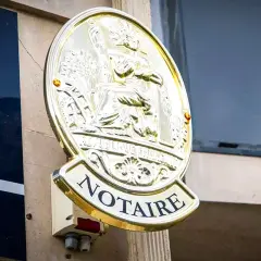Plaque dorée "NOTAIRE" sur un mur. Une image qui pourrait évoquer un détournement d'héritage par notaire, une affaire sombre.