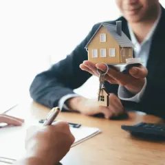 Agent présentant une maquette de maison et des clés, symbolisant la vente du bien et le droit de retour conventionnel.