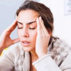 Femme se tenant les tempes, l'air soucieux. Comment toucher 100 % de son salaire en arrêt maladie ?