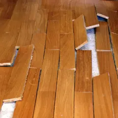 Parquet en bois abîmé, lames décollées et cassées. Une vraie malfaçon de travaux qui rend le sol dangereux.