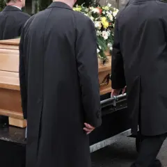Porteurs en manteaux noirs transportent un cercueil fleuri. La question "peut on être enterré dans son jardin" résonne.