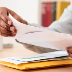 Mains ouvrant des enveloppes, peut-être une arnaque au chèque énergie ? Attention aux courriers suspects.