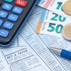 Calculatrice, billets et pièces en euros sur un bulletin de paie. Idéal pour le calcul ancienneté.