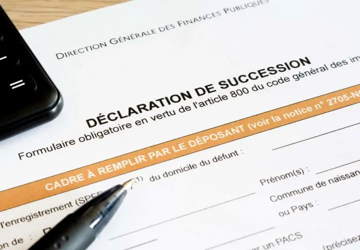 Un formulaire de déclaration de succession est prêt à être rempli, avec un stylo et un téléphone à proximité.