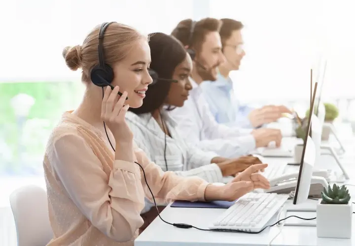 Équipe au bureau des aides régionales, en plein démarchage téléphonique. Ils sont souriants et concentrés sur leurs ordinateurs.
