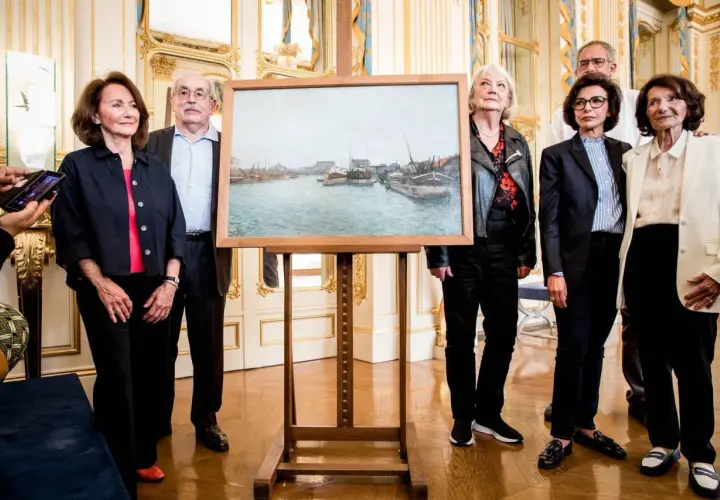 Un tableau de port, peut-être une œuvre d'art spoliée, est présenté par des personnes élégantes dans un salon doré.