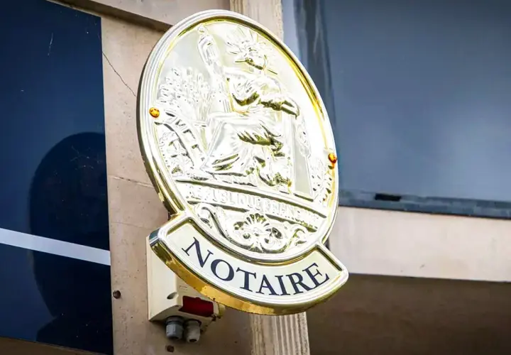 Plaque dorée "NOTAIRE" sur un mur. Une image qui pourrait évoquer un détournement d'héritage par notaire, une affaire sombre.