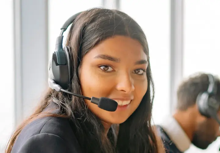 Une opératrice souriante, casque sur les oreilles, prête pour le démarchage téléphonique 06.