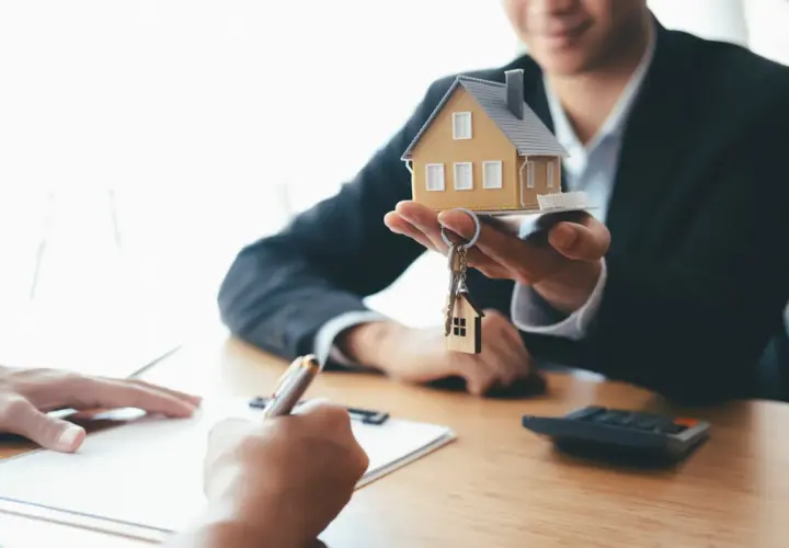 Agent présentant une maquette de maison et des clés, symbolisant la vente du bien et le droit de retour conventionnel.