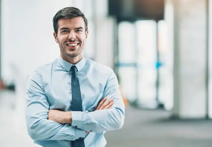 Un homme d'affaires souriant, bras croisés, incarne le rôle de mandataire social avec assurance.
