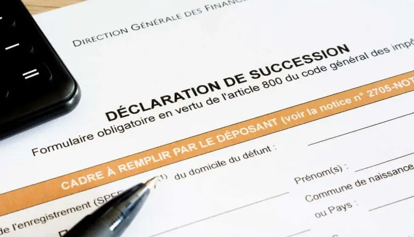 Un formulaire de déclaration de succession est prêt à être rempli, avec un stylo et un téléphone à proximité.