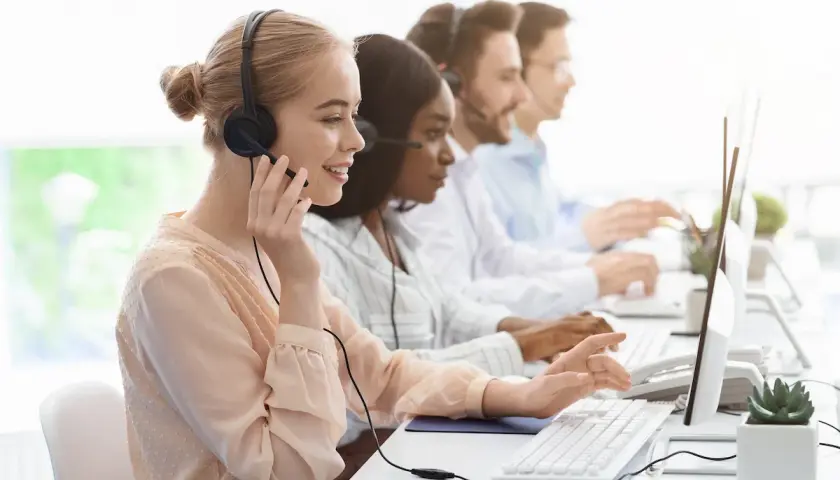 Équipe au bureau des aides régionales, en plein démarchage téléphonique. Ils sont souriants et concentrés sur leurs ordinateurs.
