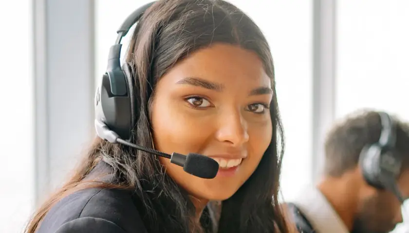 Une opératrice souriante, casque sur les oreilles, prête pour le démarchage téléphonique 06.