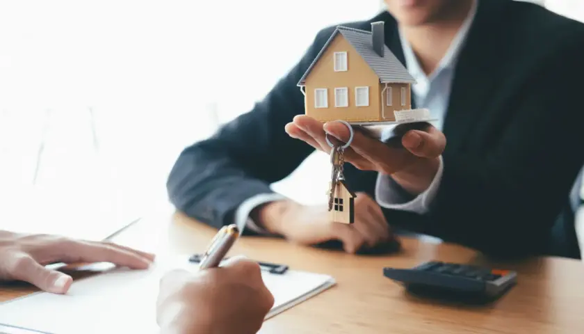 Agent présentant une maquette de maison et des clés, symbolisant la vente du bien et le droit de retour conventionnel.