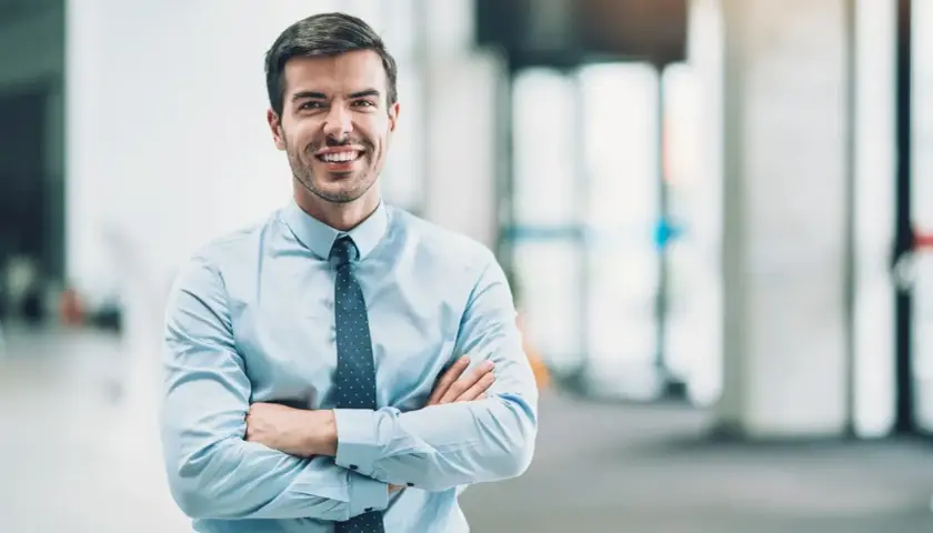 Un homme d'affaires souriant, bras croisés, incarne le rôle de mandataire social avec assurance.