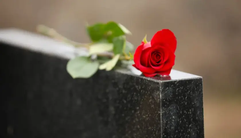 Une rose rouge sur une pierre tombale, symbole de deuil et de souvenir. Le notaire s'occupe du déblocage des fonds succession.