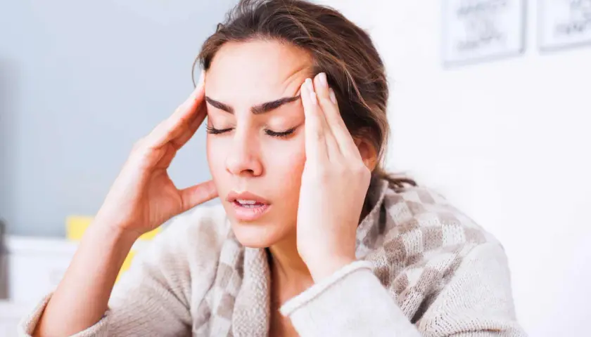 Femme se tenant les tempes, l'air soucieux. Comment toucher 100 % de son salaire en arrêt maladie ?