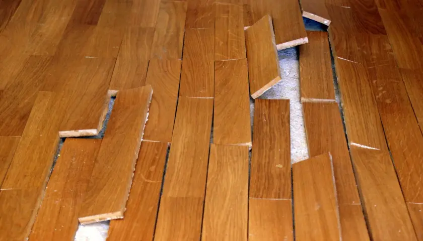 Parquet en bois abîmé, lames décollées et cassées. Une vraie malfaçon de travaux qui rend le sol dangereux.