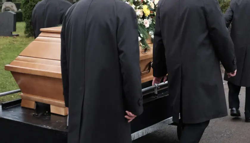 Porteurs en manteaux noirs transportent un cercueil fleuri. La question "peut on être enterré dans son jardin" résonne.
