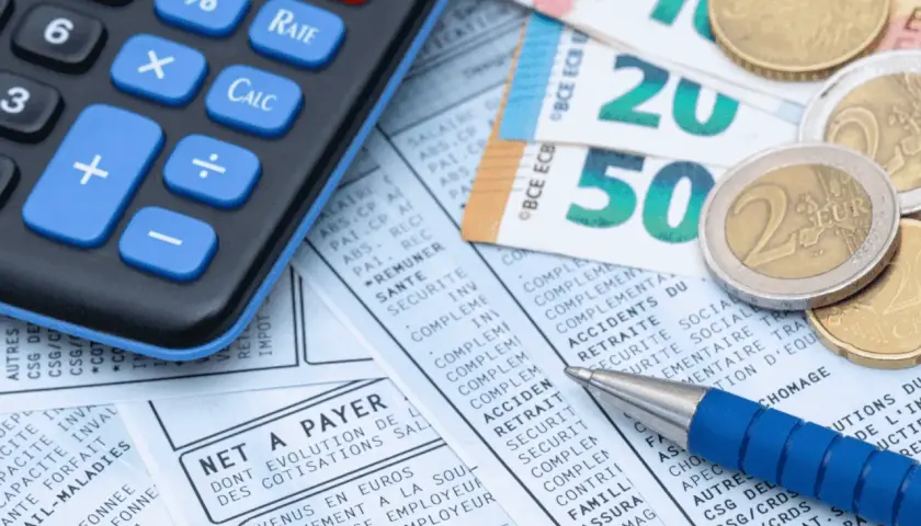 Calculatrice, billets et pièces en euros sur un bulletin de paie. Idéal pour le calcul ancienneté.