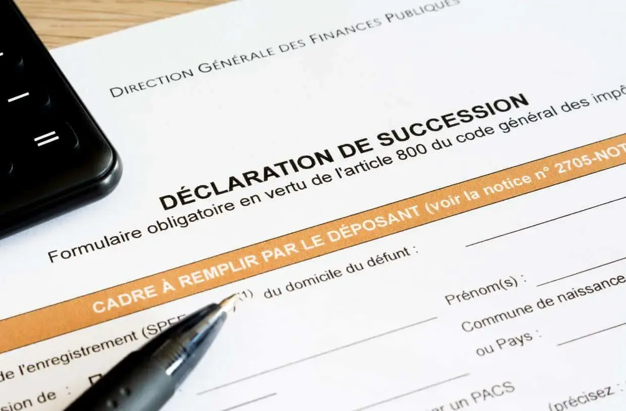 Un formulaire de déclaration de succession est prêt à être rempli, avec un stylo et un téléphone à proximité.