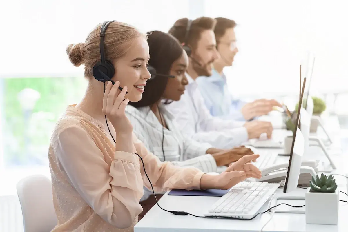 Équipe au bureau des aides régionales, en plein démarchage téléphonique. Ils sont souriants et concentrés sur leurs ordinateurs.