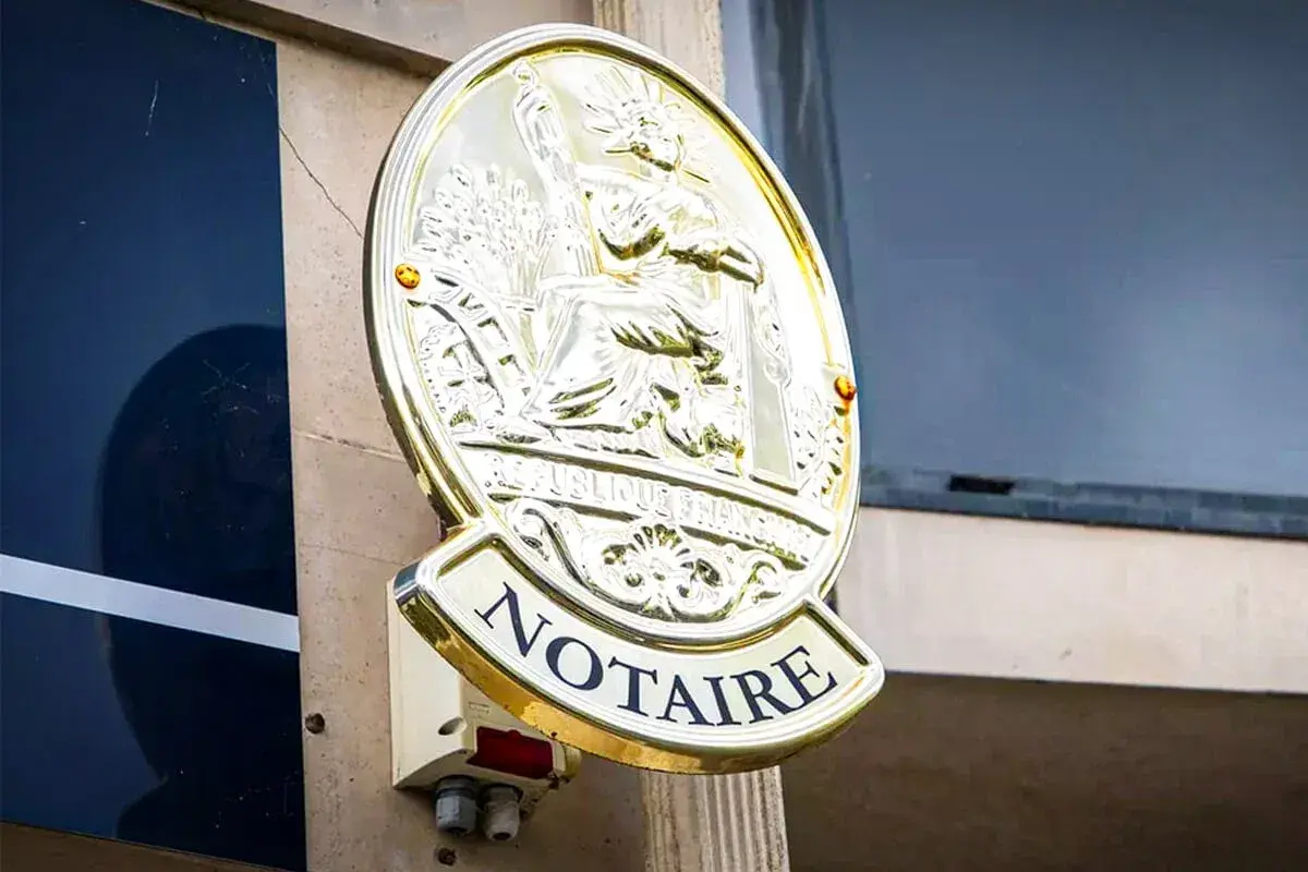 Plaque dorée "NOTAIRE" sur un mur. Une image qui pourrait évoquer un détournement d'héritage par notaire, une affaire sombre.