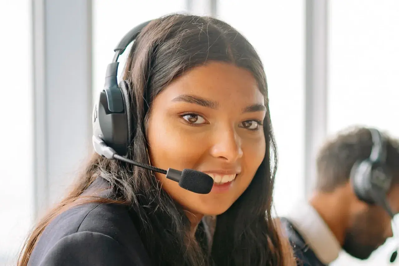 Une opératrice souriante, casque sur les oreilles, prête pour le démarchage téléphonique 06.