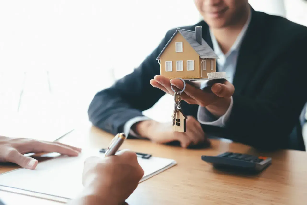 Agent présentant une maquette de maison et des clés, symbolisant la vente du bien et le droit de retour conventionnel.