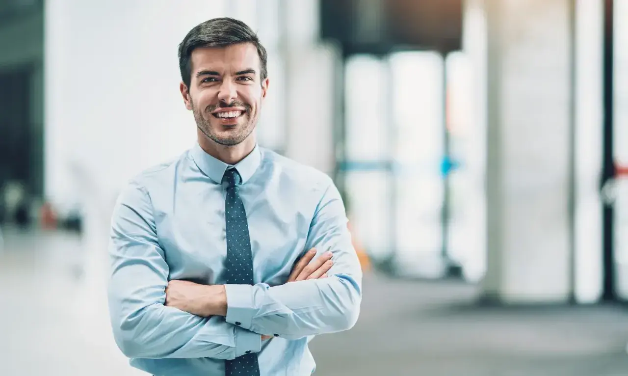 Un homme d'affaires souriant, bras croisés, incarne le rôle de mandataire social avec assurance.