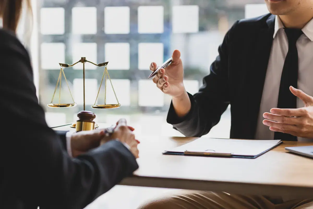 Un avocat explique un point crucial à son client, la balance de la justice en arrière-plan symbolisant un porte fort.