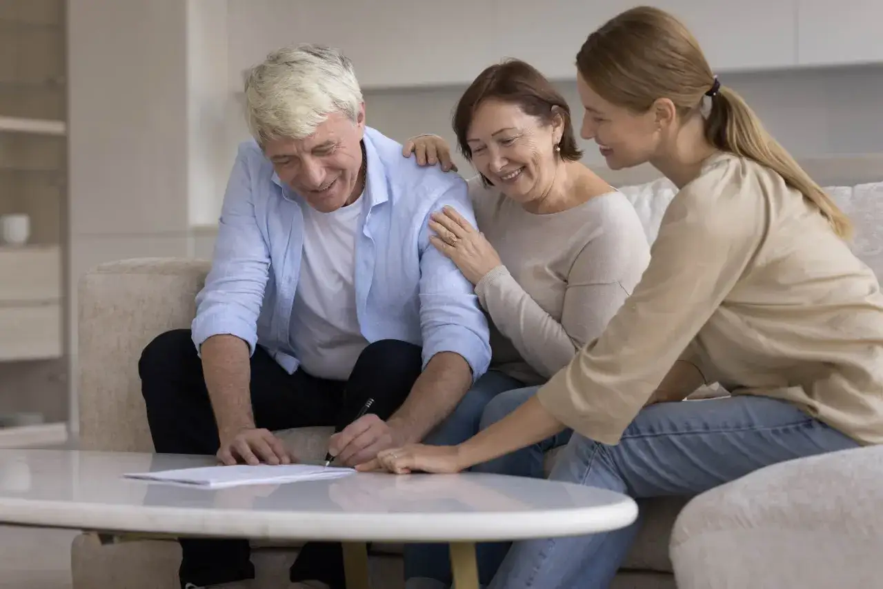 Un couple âgé signe un contrat viager avec leur fille, souriants et confiants dans leur avenir.