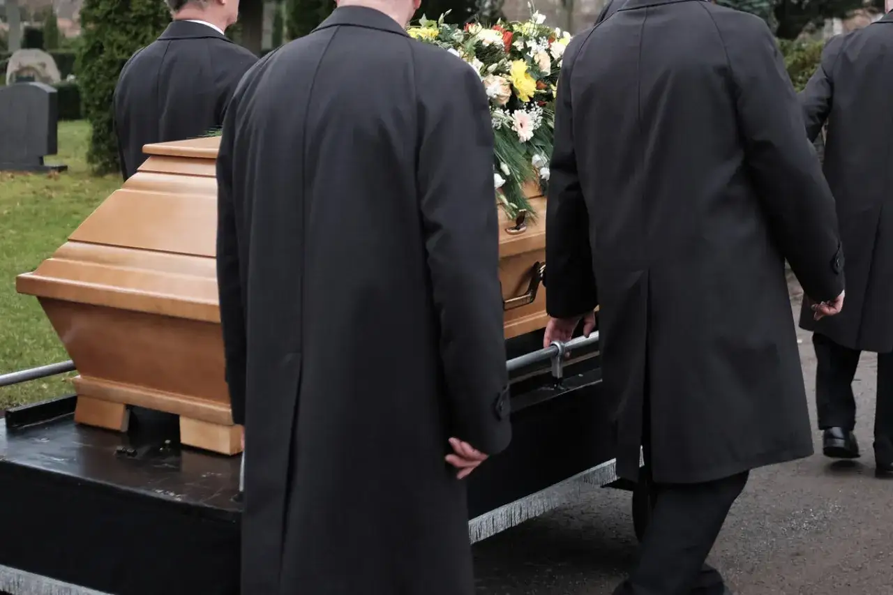 Porteurs en manteaux noirs transportent un cercueil fleuri. La question 