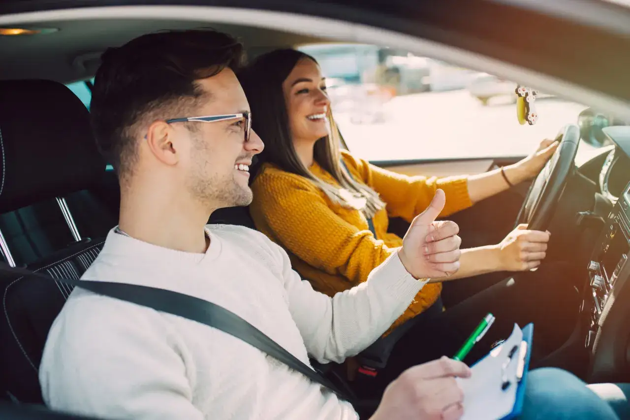 Un moniteur d'auto-école donne son approbation à une élève conductrice. Une scène de conduite normale, loin de la répression des fraudes auto-école.