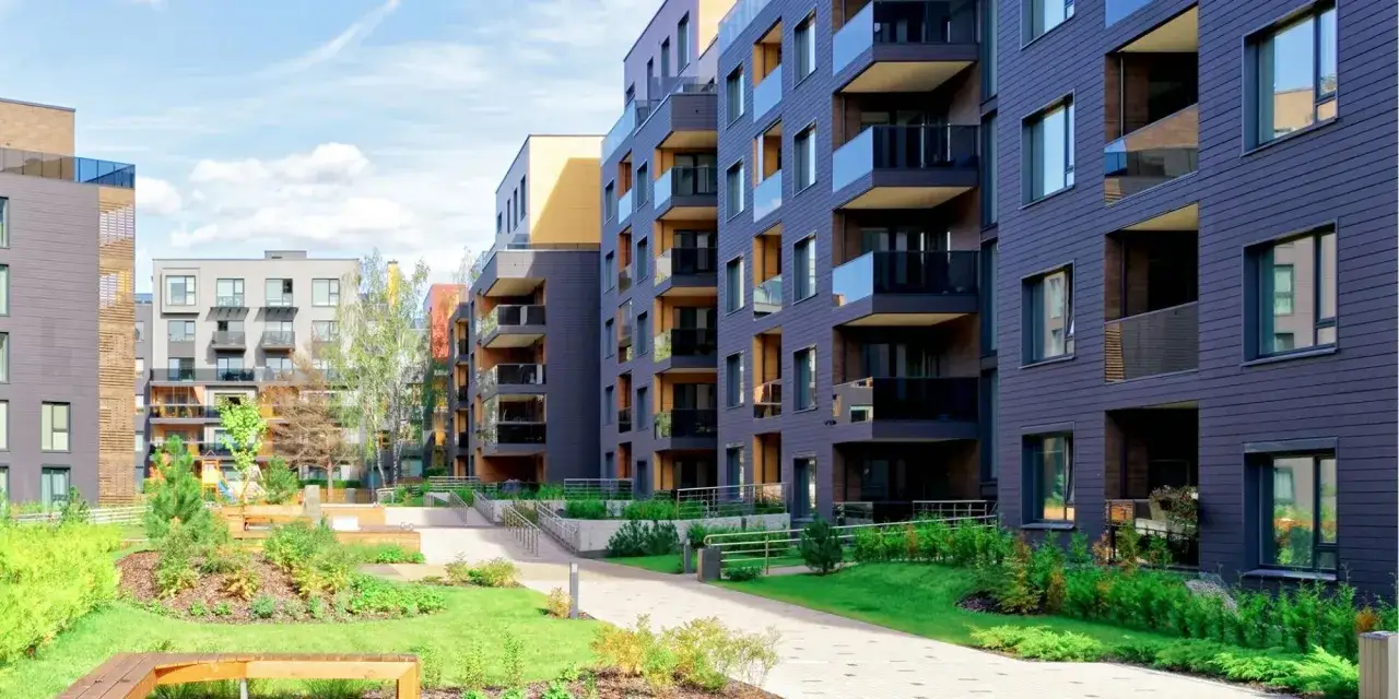 Immeubles modernes avec balcons vitrés et espaces verts. Idéal pour signaler un problème au syndic concernant l'entretien du jardin.