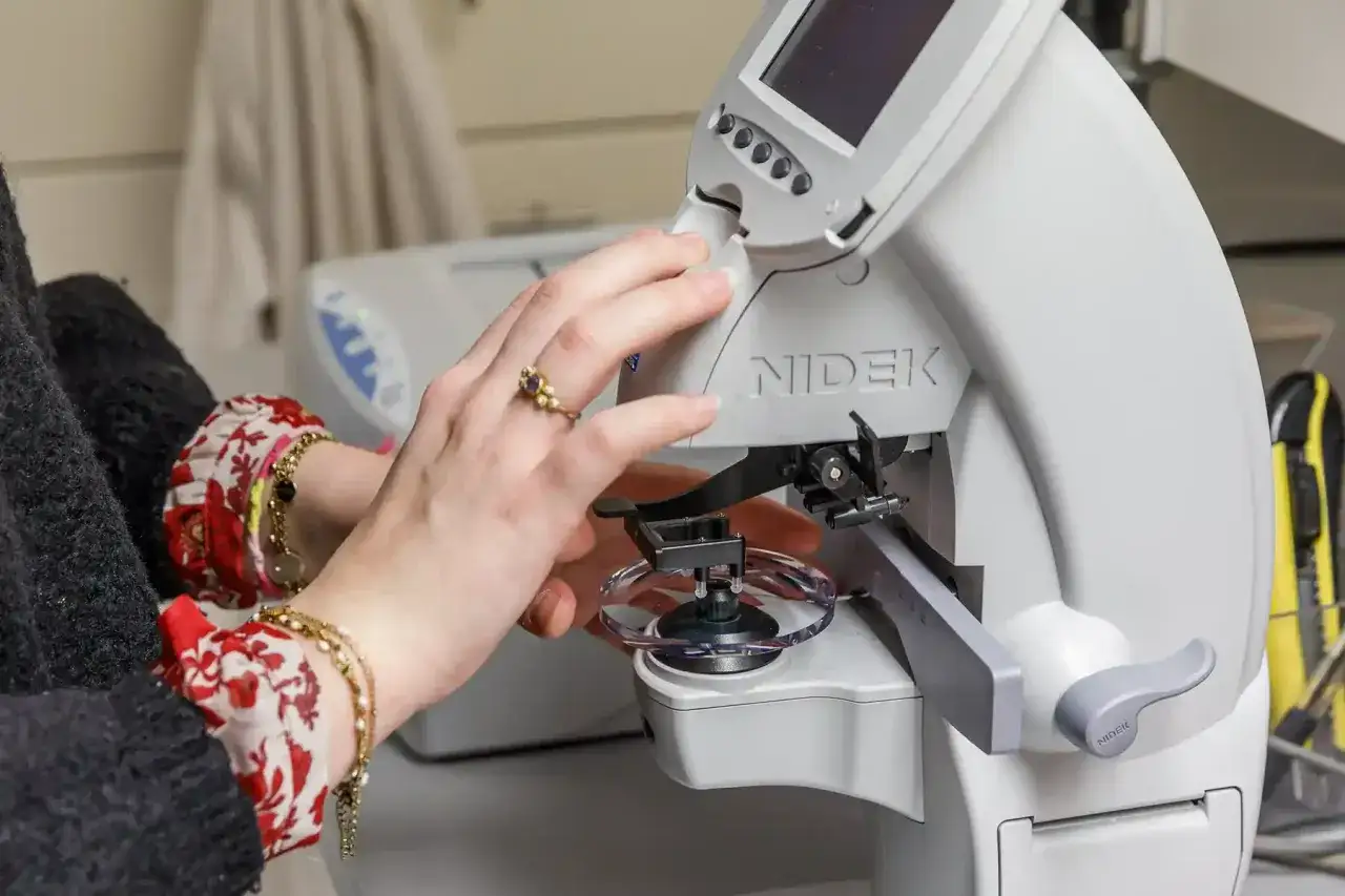 Une main ajuste une lentille sur une machine Nidek. Si vos lunettes sont mal faites, quel recours avez-vous ?