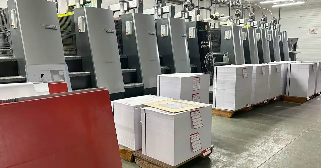 Imprimerie de labeur : presses Heidelberg Speedmaster align&eacute;es, piles de papier pr&ecirc;tes &agrave; l'impression.